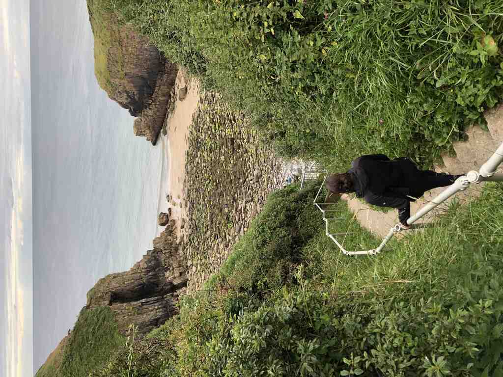 Kathi geht eine steile Stiege hinunter zu einer engen Bucht mit steilen Klippen