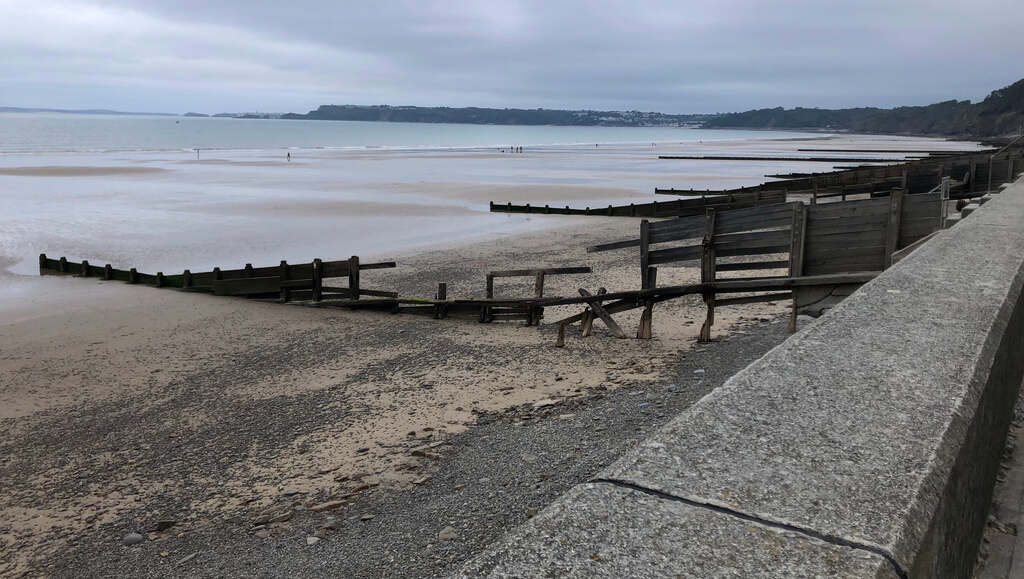 Ein Strand unterteilt von langen baufälligen Holzzäunen die ins Meer laufen