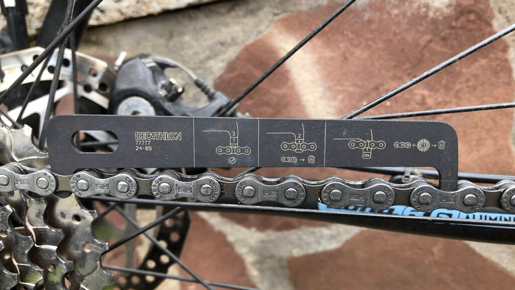 Nahaufnahme einer Kettenlehre die auf einer neuen Fahrradkette liegt
