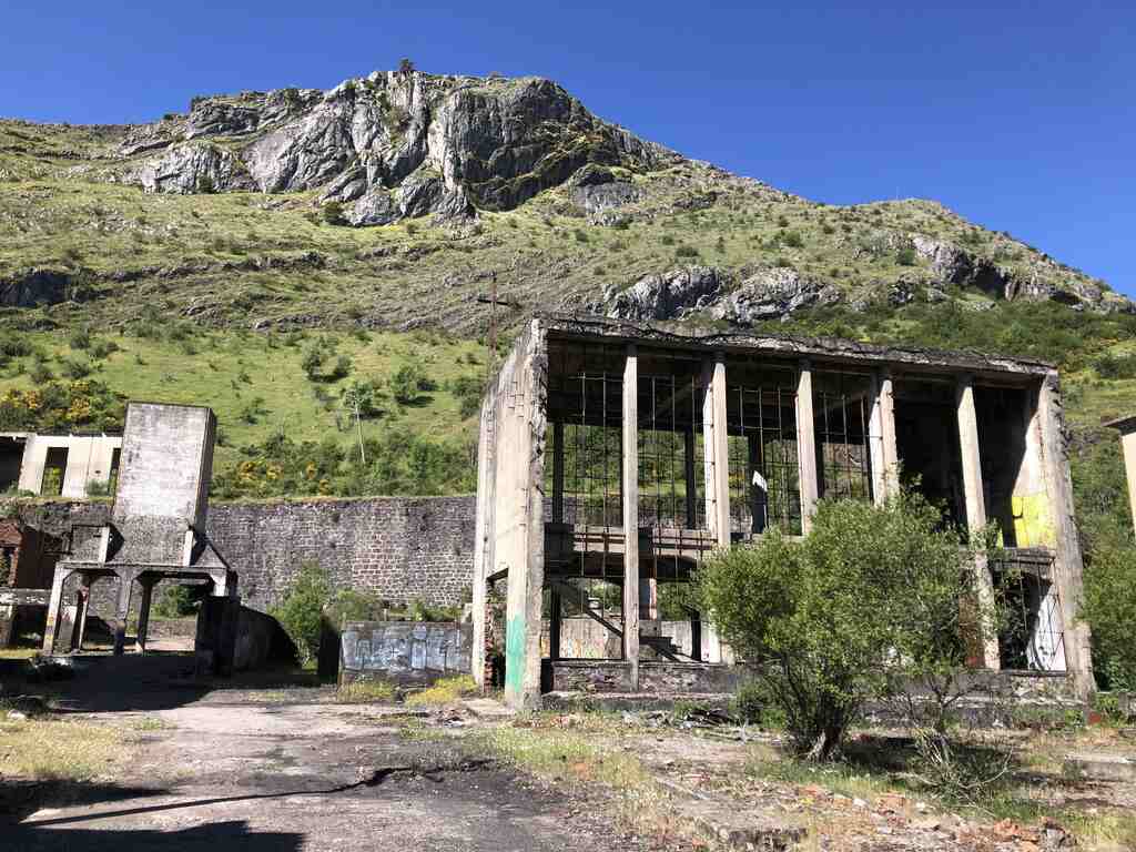 Ruine eines Fabrikgebäudes vor einem Berghang