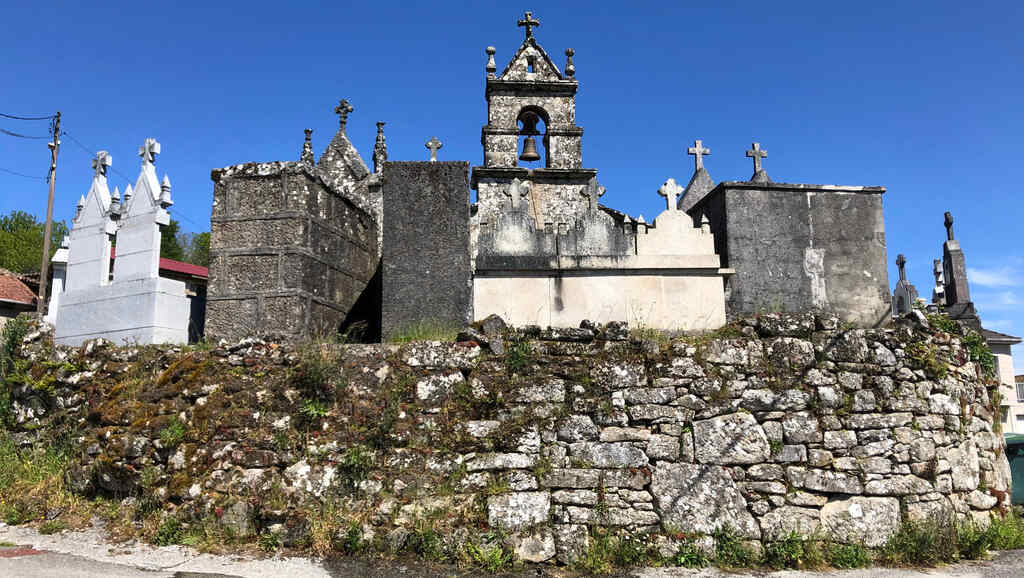 Eine verwitterte kleine Kirche umringt von Grabsteinen