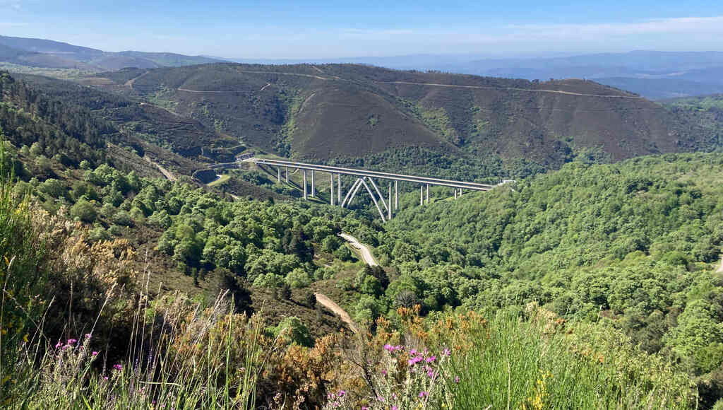 Ein Viadukt zwischen bewaldeten Hügeln verbindet zwei Eisenbahntunnel