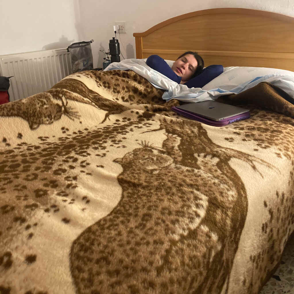 Kathi liegt im Bett bedeckt von einer braunen Decke mit Leopardenmotiv