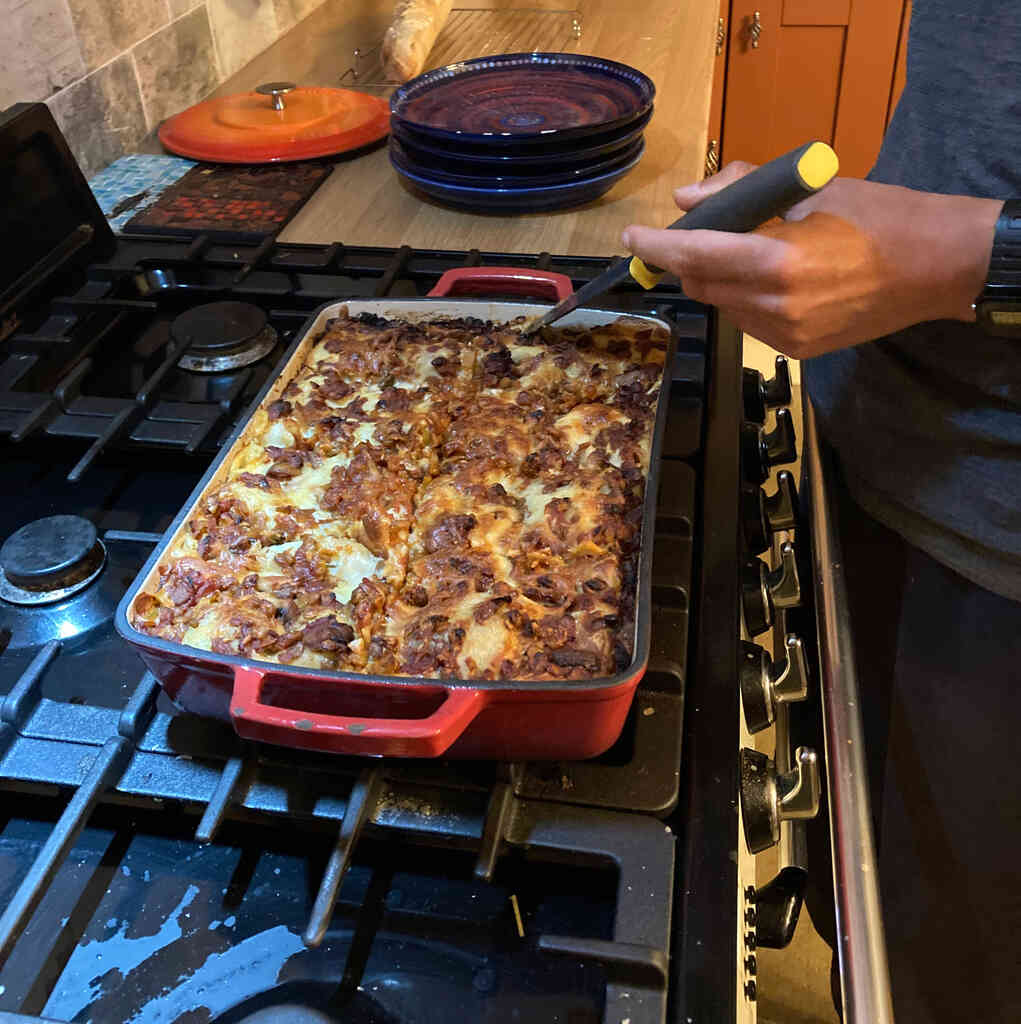 Eine Terrine voll Lasagne steht auf einem Gasherd