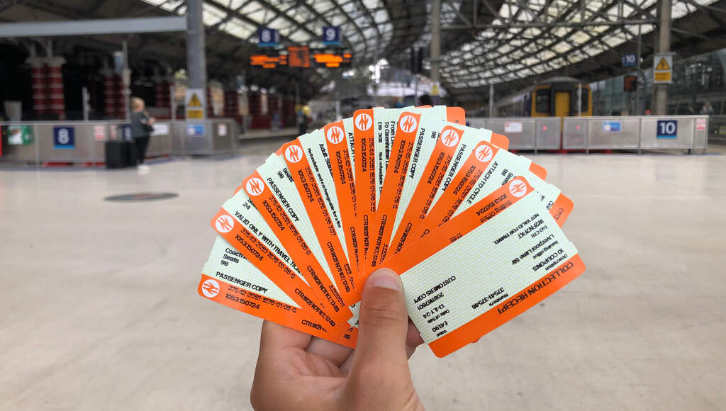 Acht kleine orange-beige Zugtickets fächerförmig in einer Hand gehalten