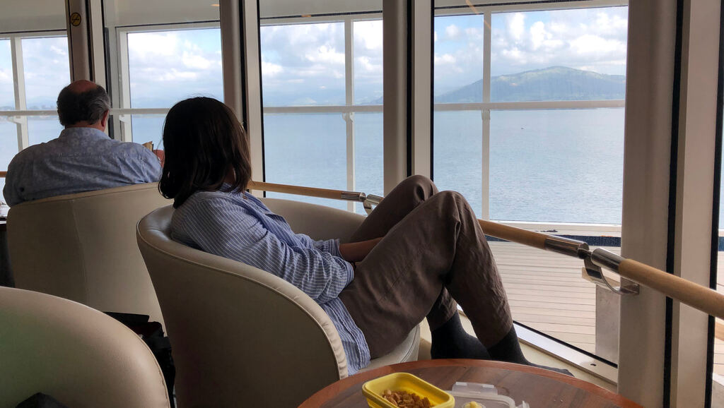 Kathi sitzt in einem Ledersessel und schaut durch das Fenster aufs Meer