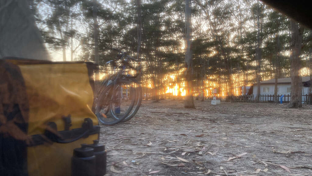 Foto durchs Mosquitonetz aus dem Zelt heraus in den Sonnenuntergang