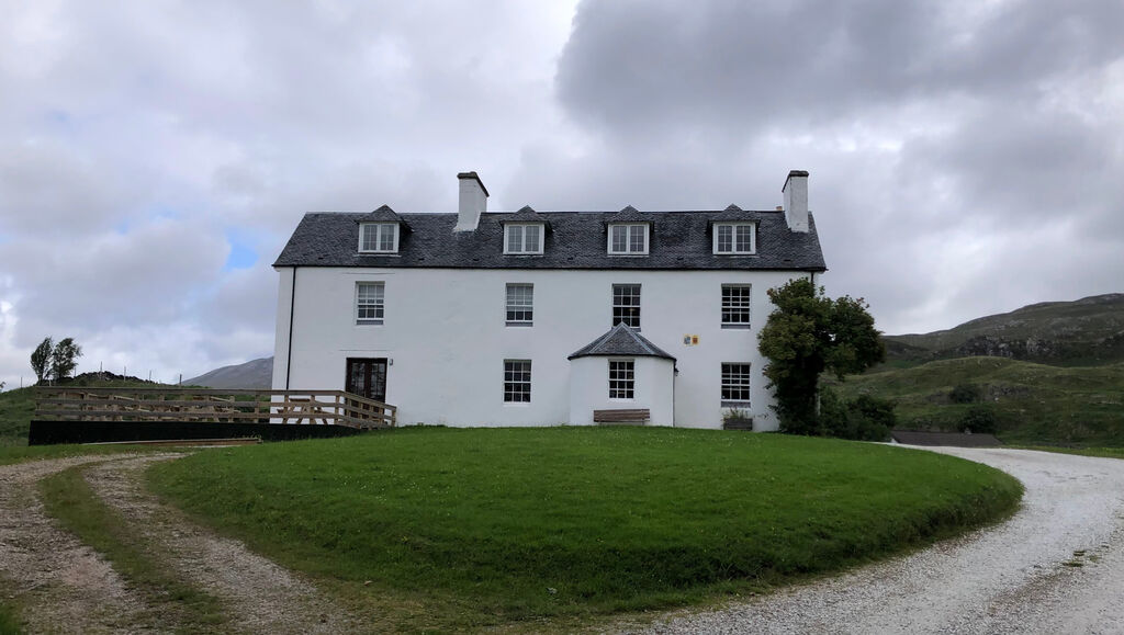 Ein freistehendes dreistöckiges Haus mit weißer Fassade und dunklem Schieferdach