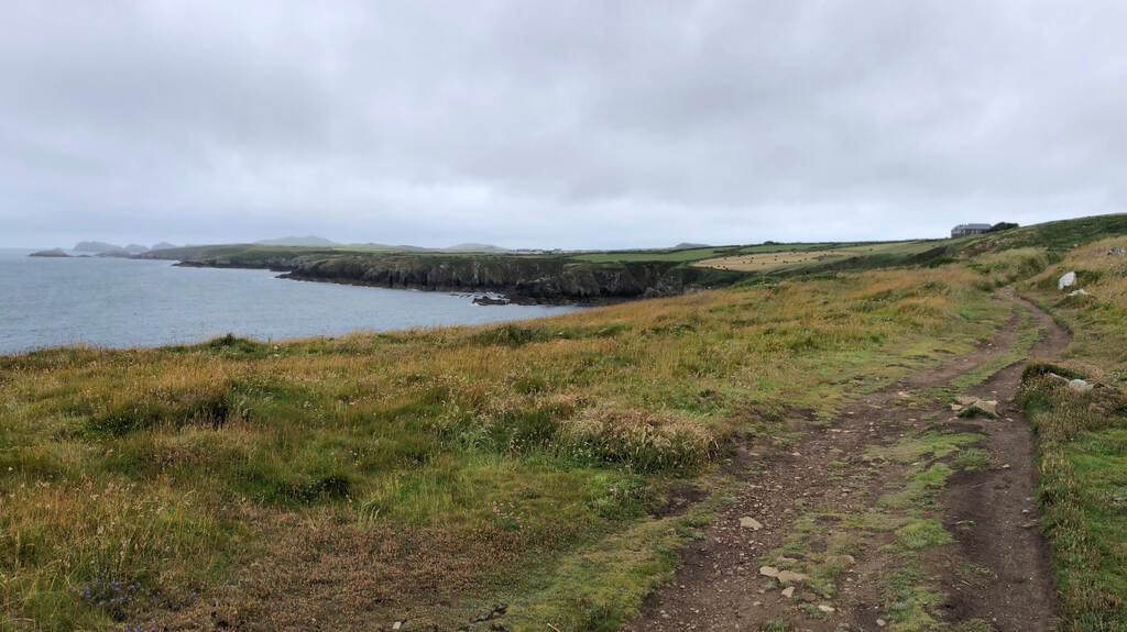 Ein Erdweg hoch überm Meer, in der Ferne Steilklippen