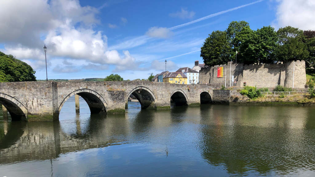 Eine dicke Steinbrücke, an deren Ende Burgmauern