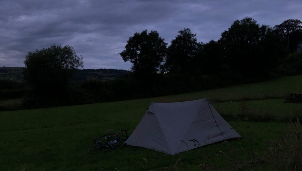 Ein Zelt in der tiefen Dämmerung auf einer Wiese