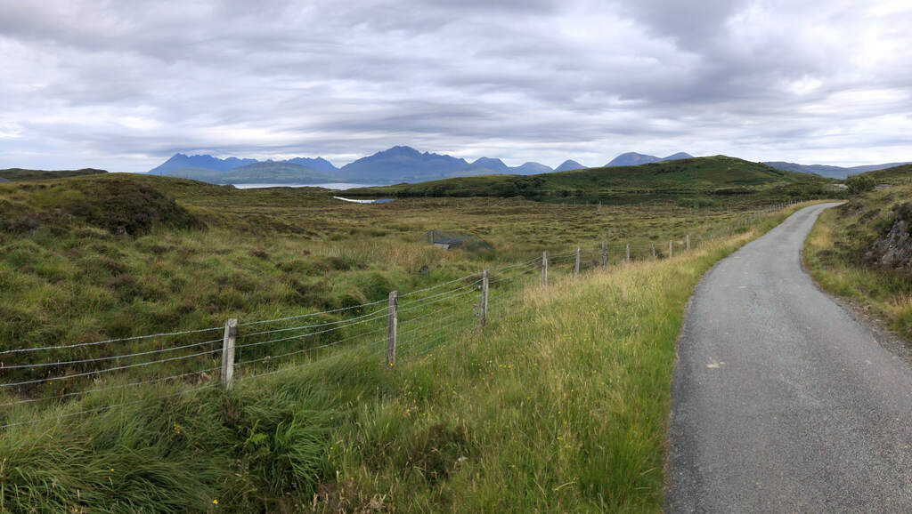 Eine Straße führt durch eine Moorlandschaft, am Horizont eine zerklüftete Bergkette