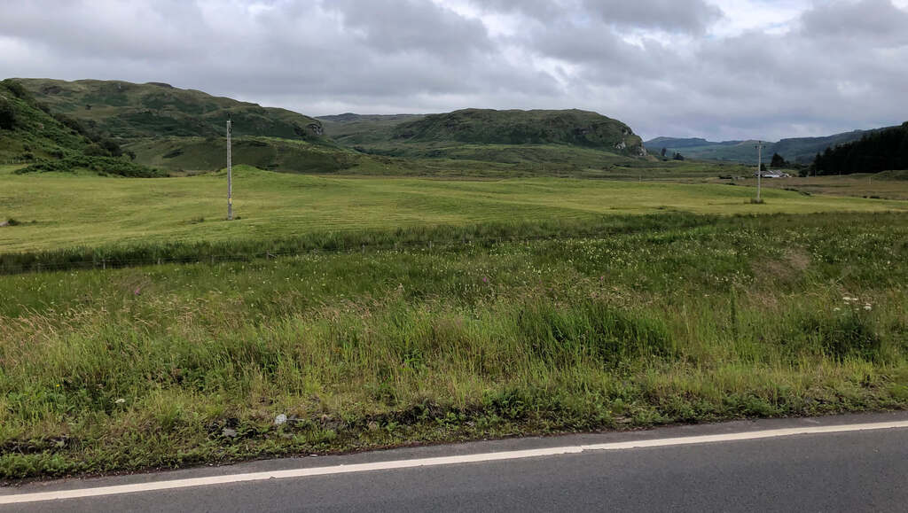 Weite Graslandschaft die in schroffe Hügel übergeht