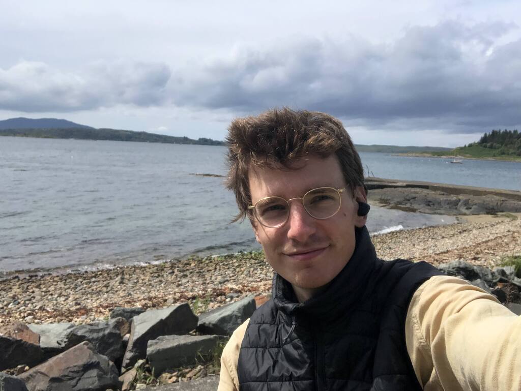 Selfie von Eli vor einem sonnigen Kiesstrand