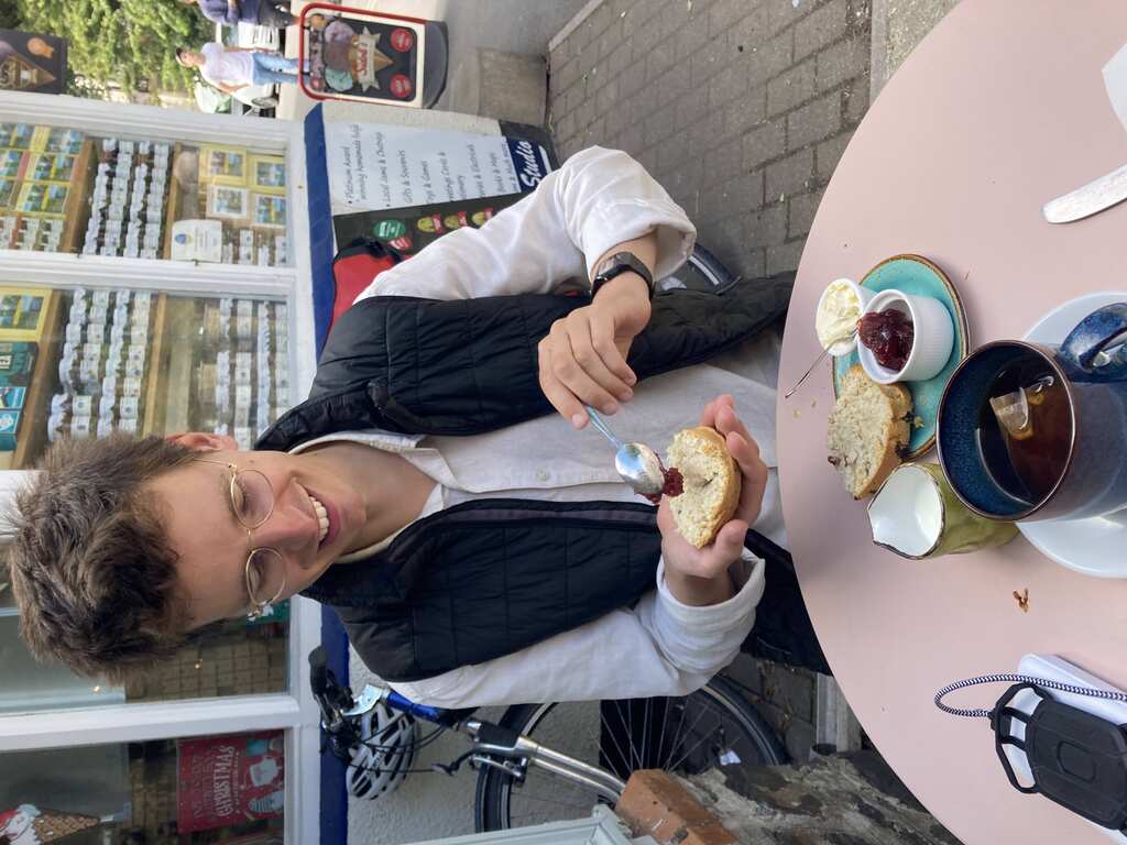 Eli hält einen Scone und gibt Marmelade drauf