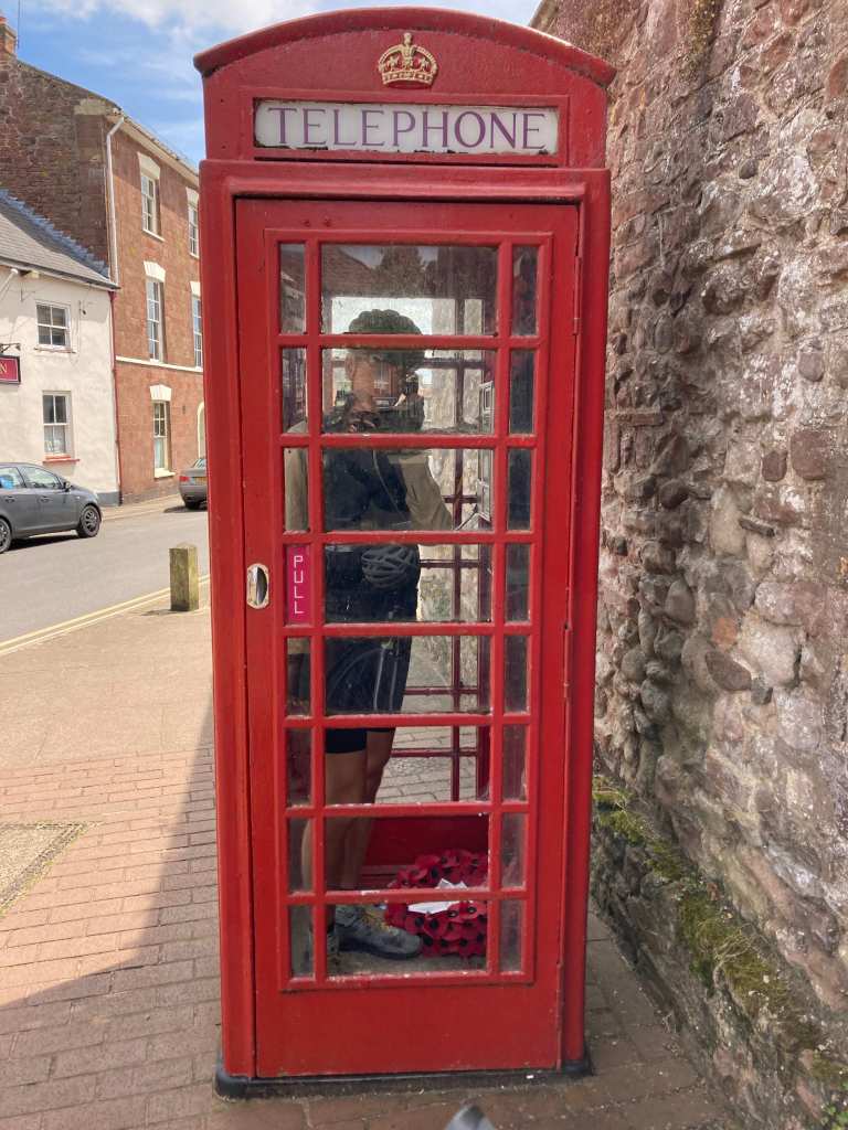 Eli steht in einer roten englischen Telefonzelle