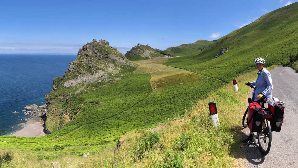 Kathi an einer Straße über einem weiten Tal, rechts Felsen die steil ins Meer abfallen