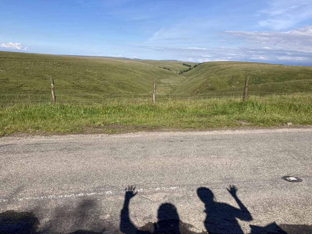 Kath und Elis winkende Schatten auf einer Straße, im Hintergrund Moorland