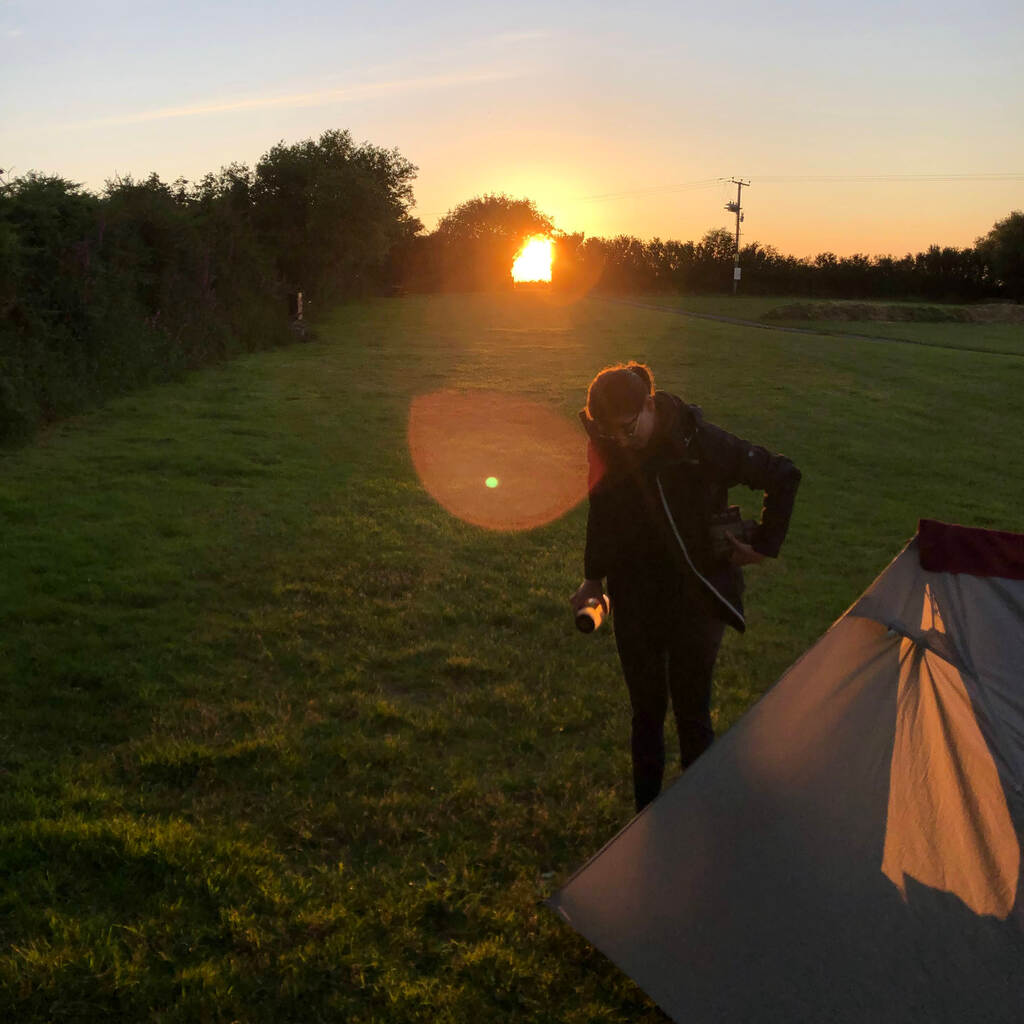 Kathi steht im Sonnenuntergang vorm Zelt