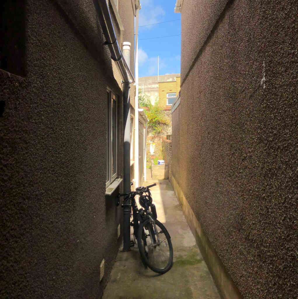 Blick aus dem Fenster in einen engen finsteren Hof, zwei Räder an eine Regenrinne gekettet