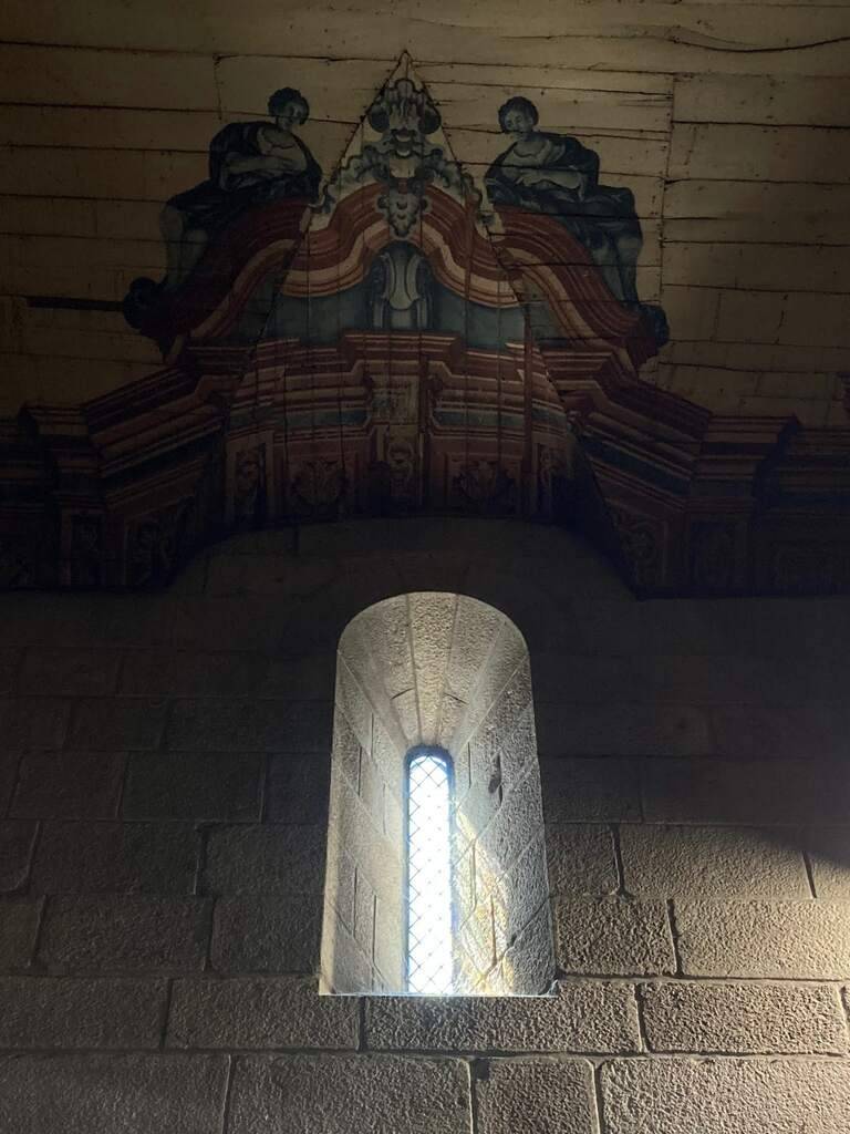 Sonnenlicht fällt durch ein kleines Fenster in der Kathedrale von Braga, darüber eine Holzvertäfelung