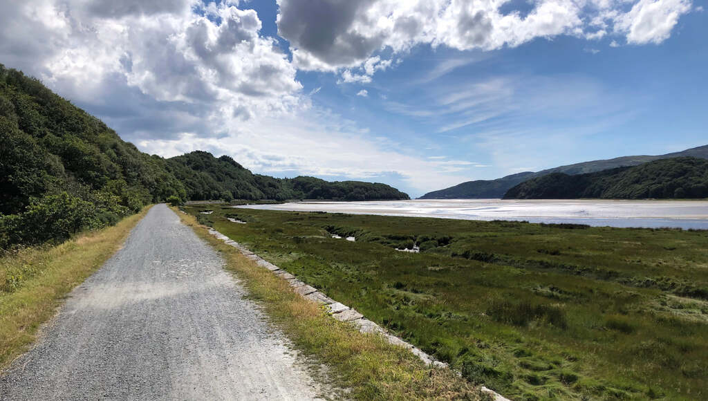 Ein Schotterweg führt einer weiten Wasserfläche entlang